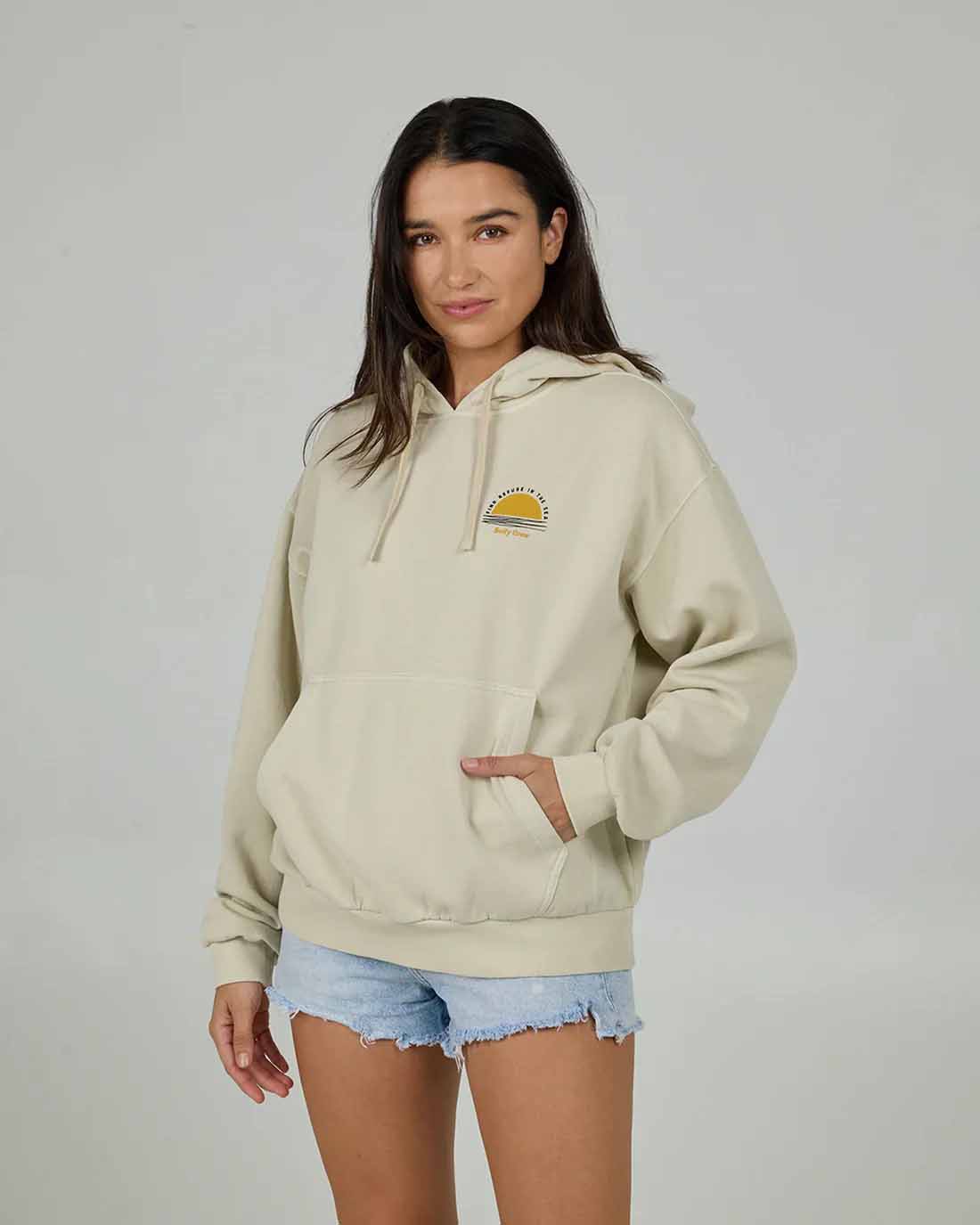 Woman wearing oversized beige hoodie with denim shorts, casual women’s streetwear NZ outfit