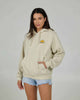 Woman wearing oversized beige hoodie with denim shorts, casual women’s streetwear NZ outfit